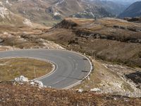 there is a winding road with many cars on it in the mountains above mountains and hills