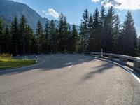 a mountain road with trees and a bench and trees to the side of the road