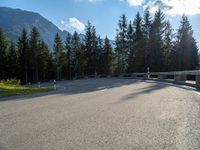 a mountain road with trees and a bench and trees to the side of the road