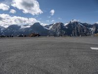 an airport runway with people standing around on it with the mountains in the background and in the distance