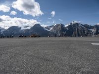 an airport runway with people standing around on it with the mountains in the background and in the distance