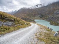 a dirt road in the middle of an alpine mountain range with a lake between two mountains