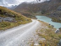 a dirt road in the middle of an alpine mountain range with a lake between two mountains