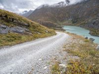 a dirt road in the middle of an alpine mountain range with a lake between two mountains