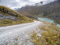 a dirt road in the middle of an alpine mountain range with a lake between two mountains