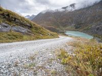 a dirt road in the middle of an alpine mountain range with a lake between two mountains