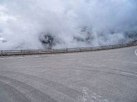 a car traveling down a highway next to an ocean with lots of smoke coming out of the clouds