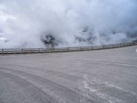 a car traveling down a highway next to an ocean with lots of smoke coming out of the clouds