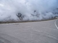 a car traveling down a highway next to an ocean with lots of smoke coming out of the clouds