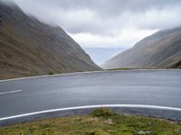 a curve on an empty mountain road next to a mountain range in the middle of an empty area