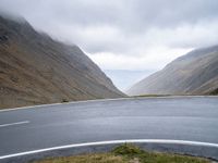 a curve on an empty mountain road next to a mountain range in the middle of an empty area