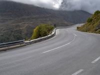 a street lined with trees and hills on either side of a road under a cloudy sky