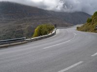 a street lined with trees and hills on either side of a road under a cloudy sky