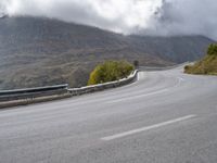 a street lined with trees and hills on either side of a road under a cloudy sky