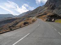 an empty highway going to a mountain pass in the mountains with a lone rider on it