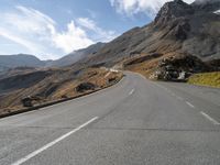 an empty highway going to a mountain pass in the mountains with a lone rider on it