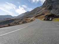 an empty highway going to a mountain pass in the mountains with a lone rider on it