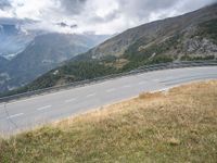 motorcycle rider on the edge of a mountain pass above a hilly valley, and the road is below