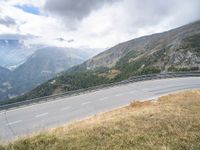 motorcycle rider on the edge of a mountain pass above a hilly valley, and the road is below