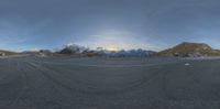 a wide angle view of the road with a mountain backdrop and a snow capped mountain range