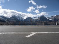 a view of the snow - capped mountains of a mountain range from a highway with a traffic sign