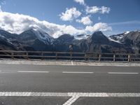 a view of the snow - capped mountains of a mountain range from a highway with a traffic sign