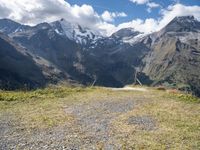 the mountains surrounding the field are rocky and there is grass on the ground beneath it