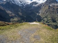 the mountains surrounding the field are rocky and there is grass on the ground beneath it