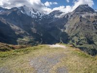 the mountains surrounding the field are rocky and there is grass on the ground beneath it