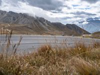 some motorcyclists on the road in the mountains with clouds and the snow capped mountains behind them