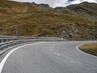 a very winding mountain road by a fenced off road with steep slope in the distance