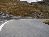 a very winding mountain road by a fenced off road with steep slope in the distance