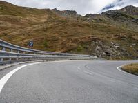 a very winding mountain road by a fenced off road with steep slope in the distance