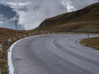 a paved road winding into the middle of the mountain landscape with a lone motorcyclist on it