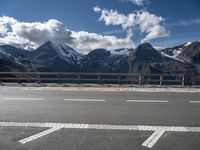 there is snow covered mountains and the road sign on it's side by some clouds