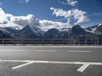 there is snow covered mountains and the road sign on it's side by some clouds