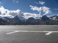 there is snow covered mountains and the road sign on it's side by some clouds