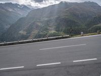 there is a man with an umbrella on the side of the road looking out over mountains