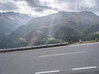 there is a man with an umbrella on the side of the road looking out over mountains