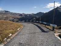 the stone road leading through mountains and valleys with benches on them that are placed near the end