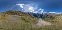 a camera panoramic view of horses grazing on the side of the road and snow capped mountains