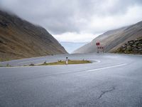 an open road, near mountains with no traffic signs on it is shown with an arrow sign