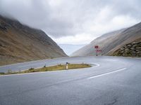 an open road, near mountains with no traffic signs on it is shown with an arrow sign