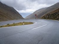 an open road, near mountains with no traffic signs on it is shown with an arrow sign