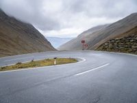 an open road, near mountains with no traffic signs on it is shown with an arrow sign