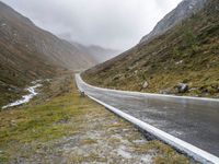 a car parked along an empty country road in the mountains in heavy rain and snow