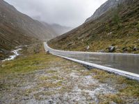 a car parked along an empty country road in the mountains in heavy rain and snow