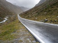 a car parked along an empty country road in the mountains in heavy rain and snow