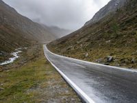 a car parked along an empty country road in the mountains in heavy rain and snow