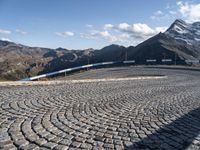 a road with cobblestone at the bottom and snowy mountains in the background,